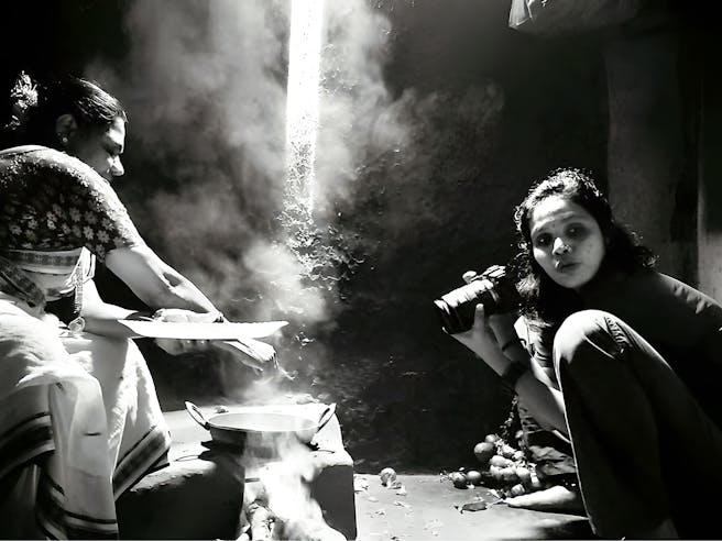 Ženska s fotoaparatom, ki fotografira drugo, ki kuha