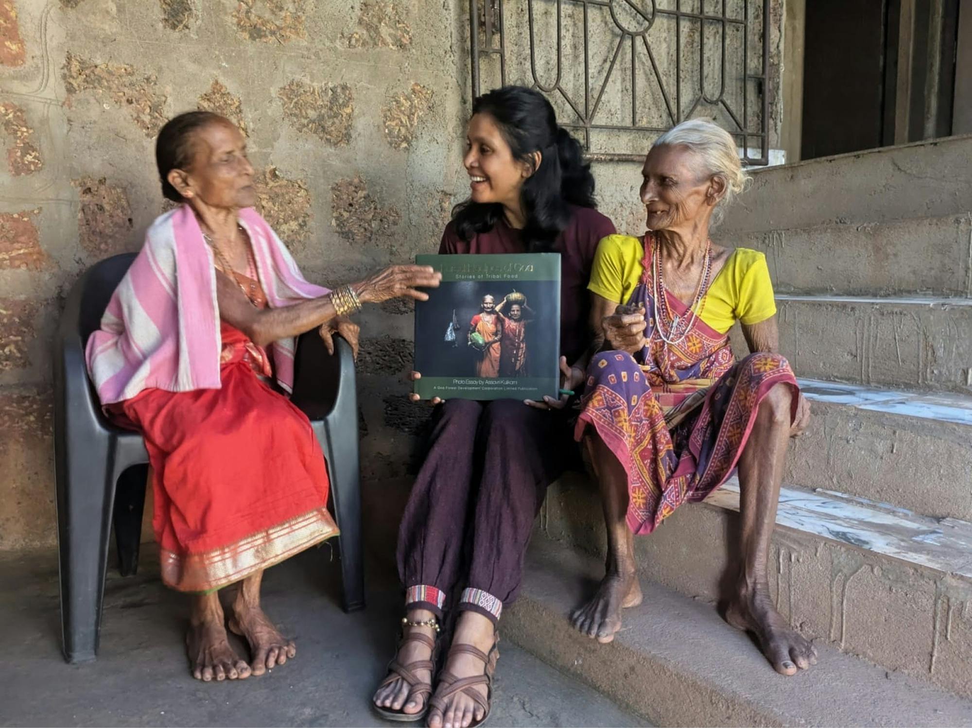 Avtorica knjige, ki sedi z dvema nasmejanima starejšima ženskama