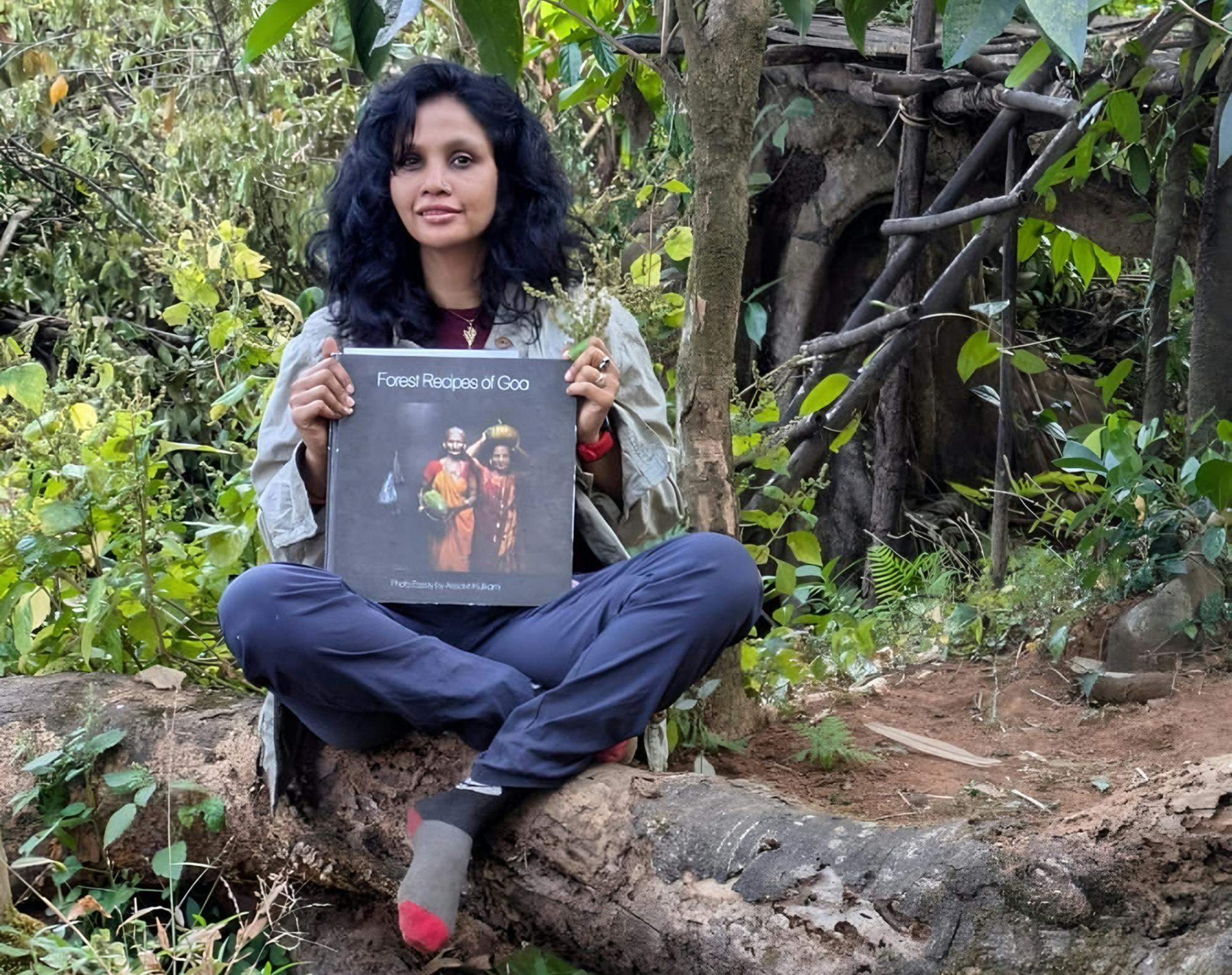Avtorica v gozdu s knjigo Forest Recipes of Goa v rokah