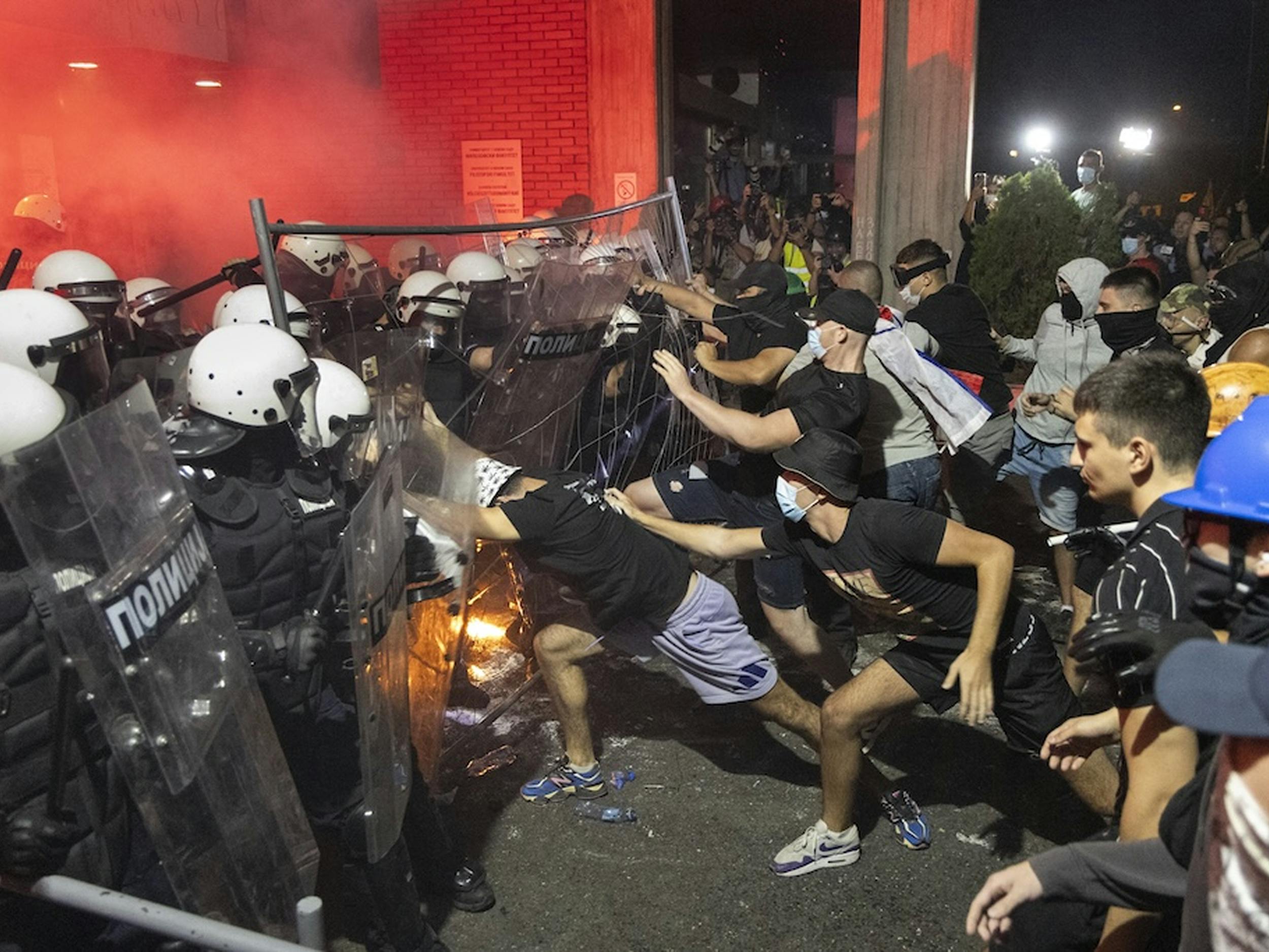 Fotografija uličnega nasilja. Na levi strani policijska barikada na desni strani ulični protestniki v momentu spopada.