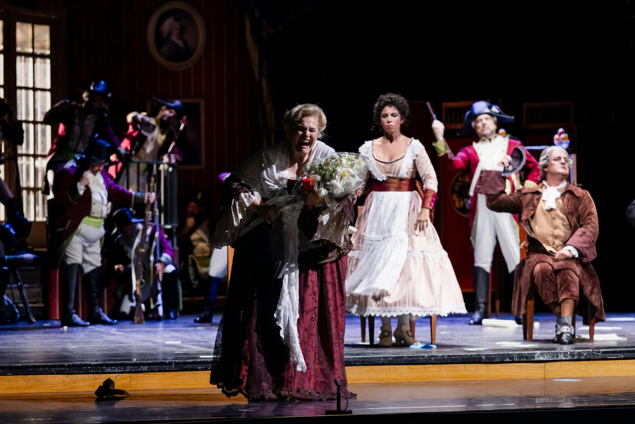 Opera na odru - v ospredju je ženska, ki kriči s šopkom rož v rokah