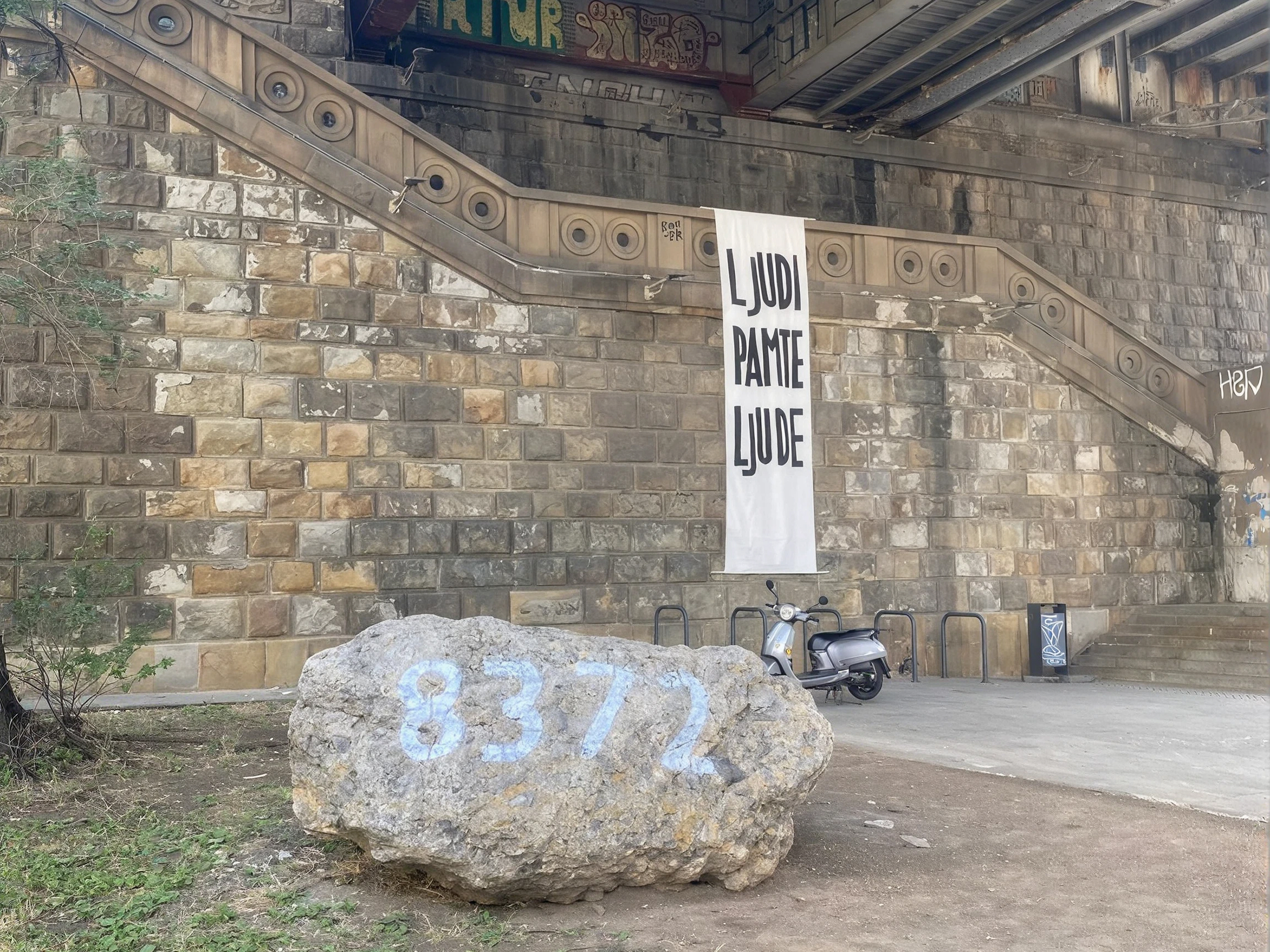 Stopnice pod mostom, s katerim visi napis Ljudi pamte ljude