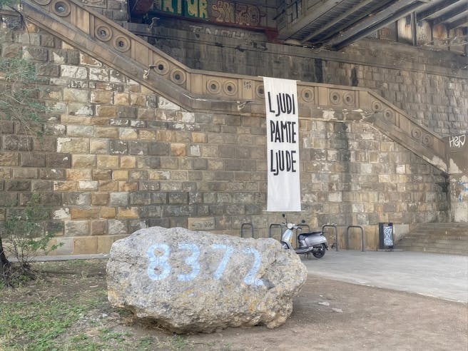 Stopnice pod mostom, s katerim visi napis Ljudi pamte ljude