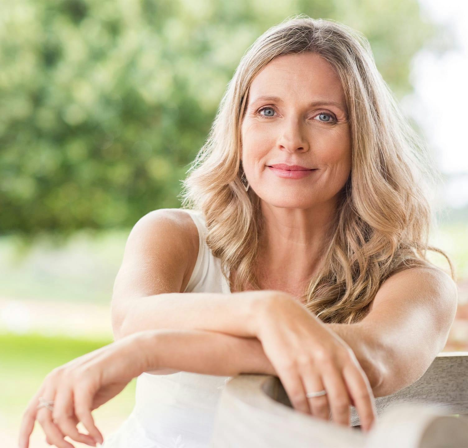 Woman smiling with arms crossed and resting on bench