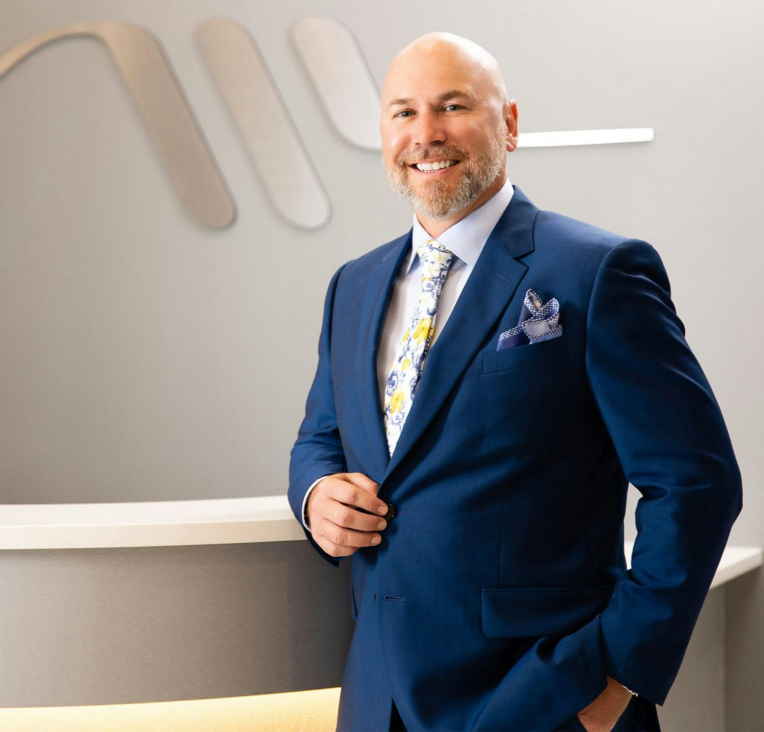 Dr. Warner Smiling in suit leaning against counter