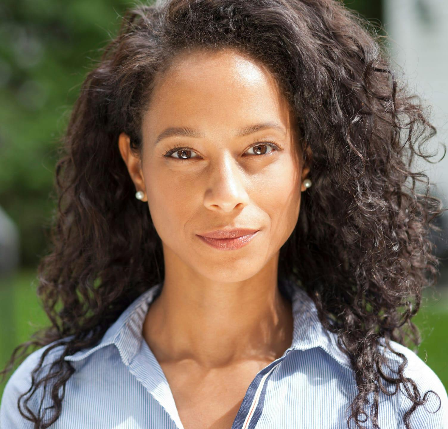 Woman smiling outside wearing blue button up shirt