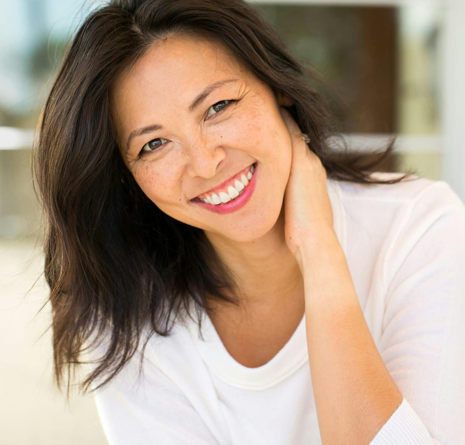 Woman smiling with hand holding her neck