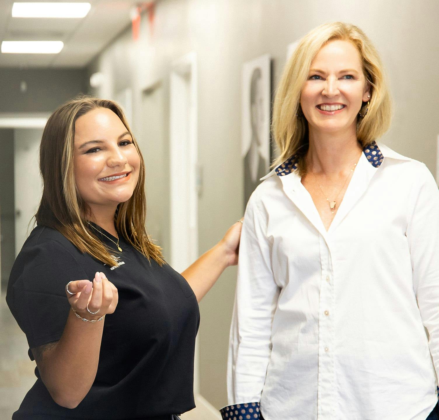 two women smiling and standing in the hallway