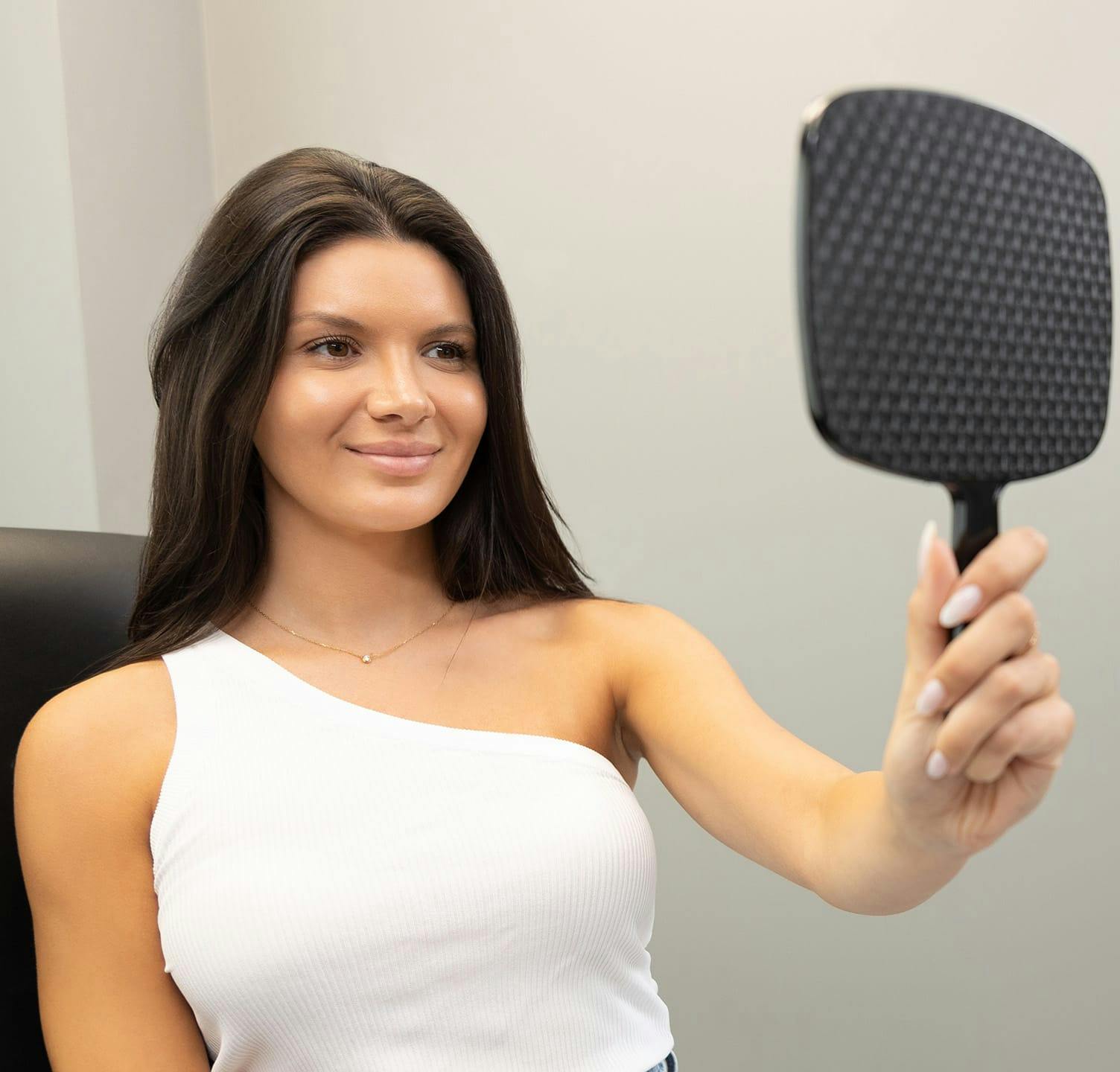 Woman smiling and looking at hand held mirror