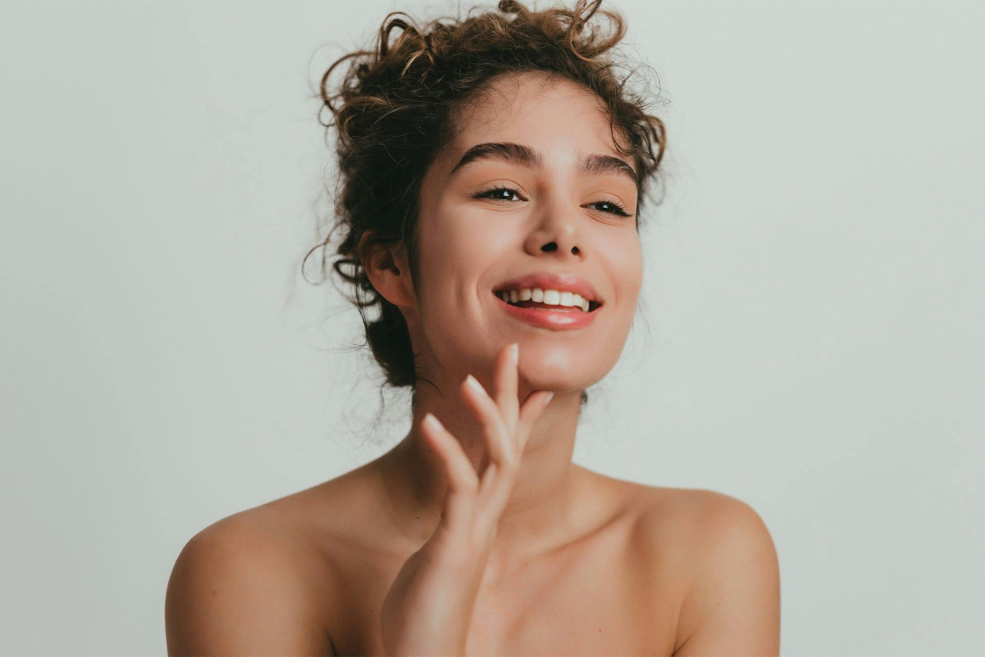 Young woman with curly hair and hand on chin