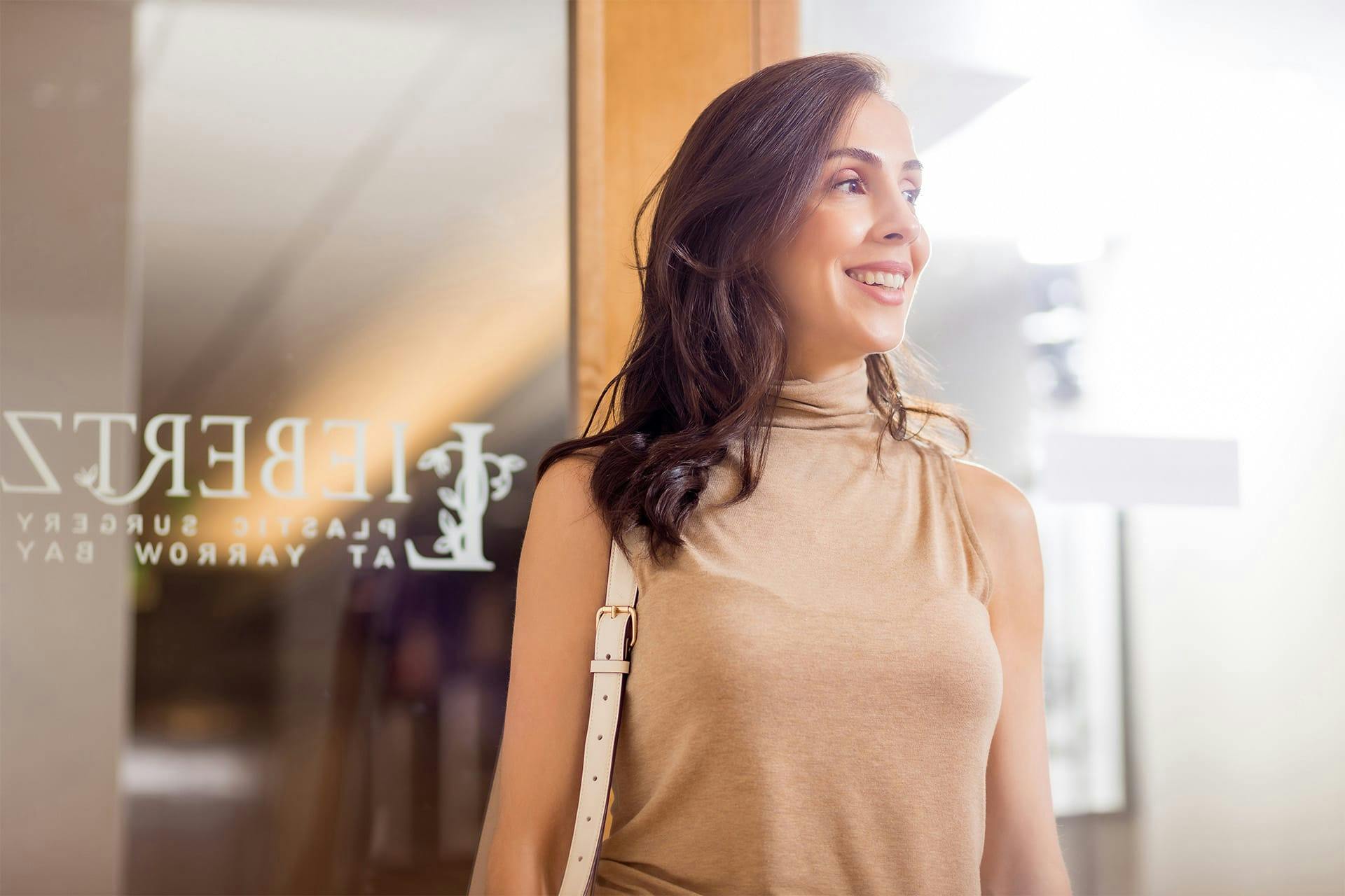 Woman in tan dress standing in front of door