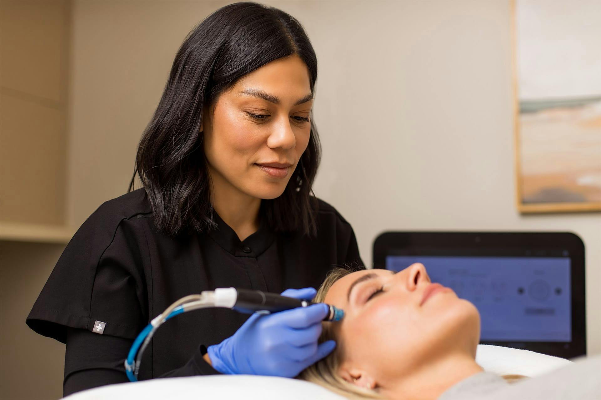 Office staff doing skin treatment with woman