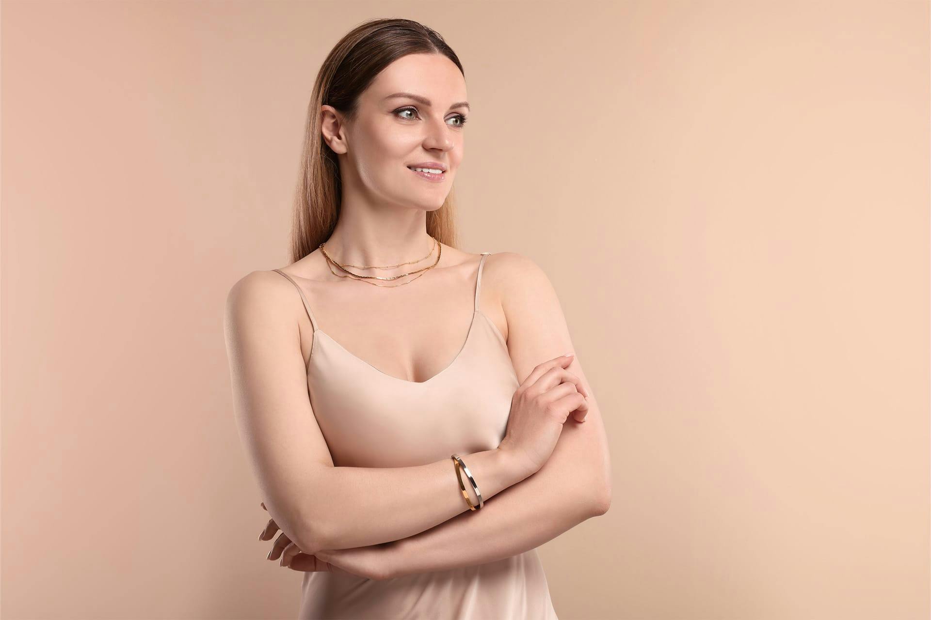 Woman posing in tan dress and gold jewelry