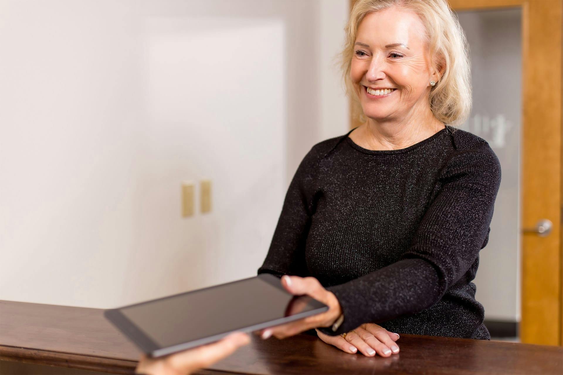 Older woman handling tablet to office staff