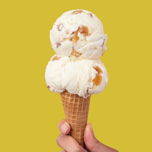 double scoop of molly moon's ginger ice cream in a sugar cone on a ginger green background