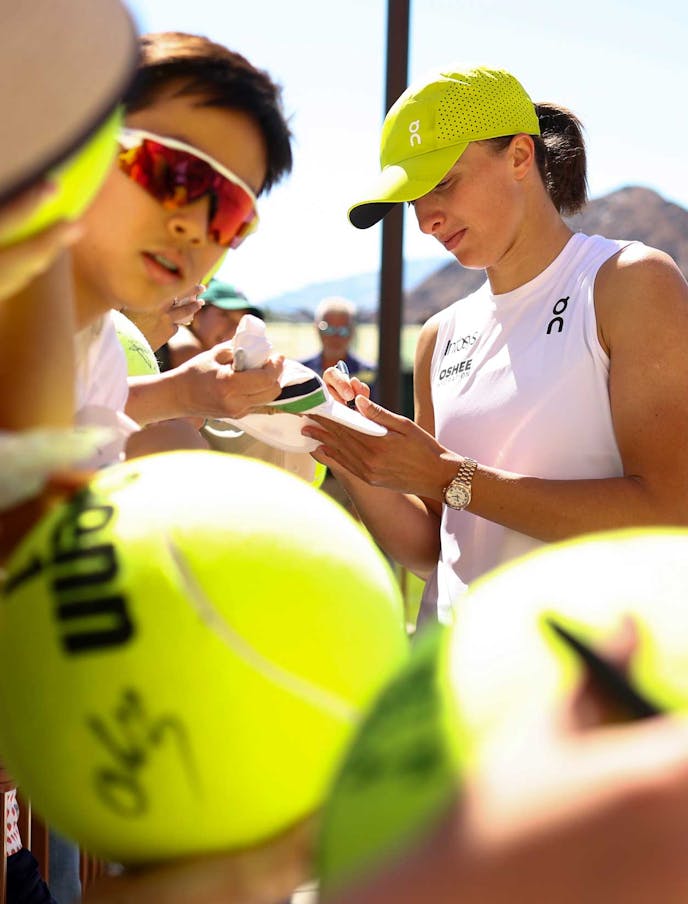 Iga Swiatek signs for fans in 2025.