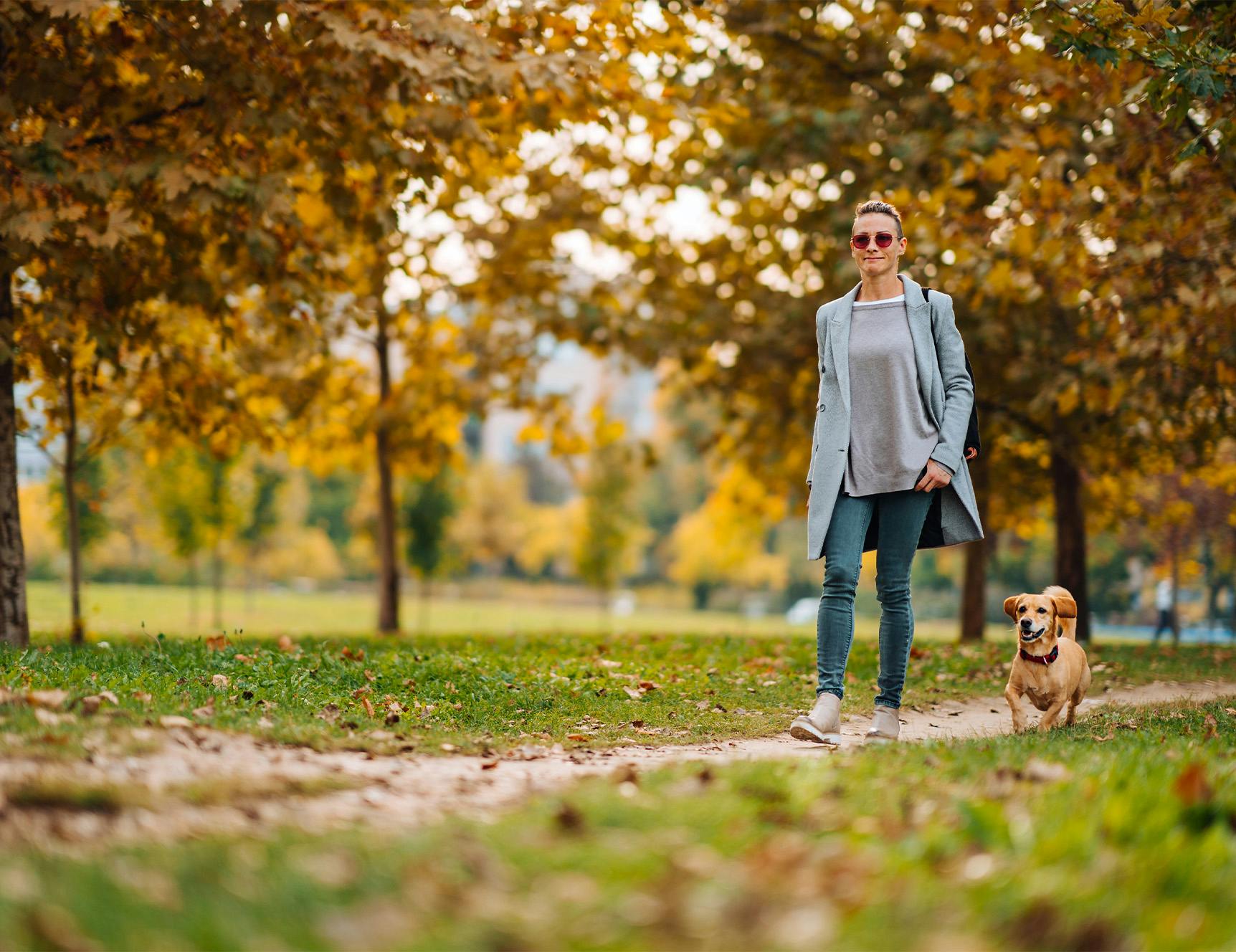 woman walking small dog at park