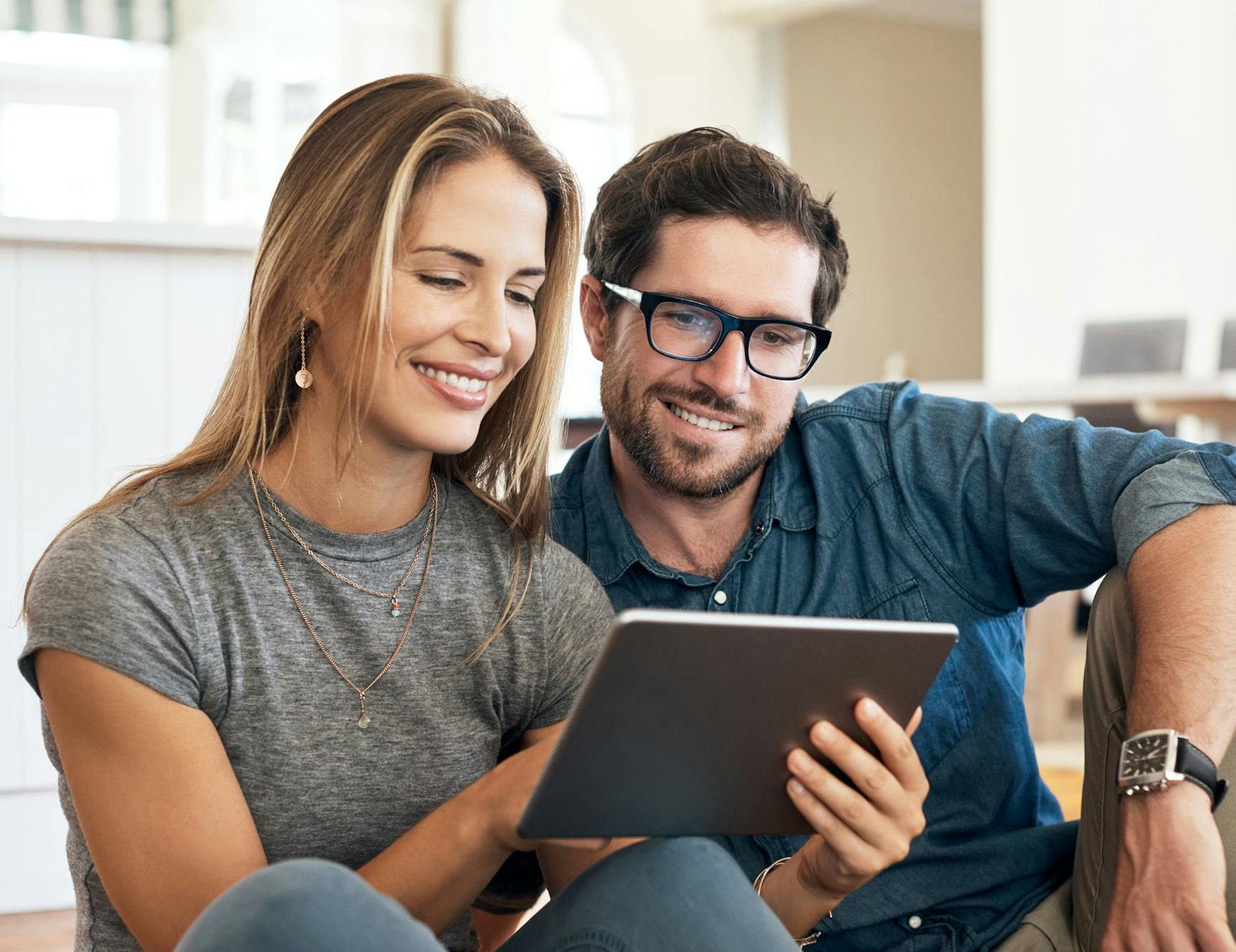 Man and woman smiling and sitting on the floor looking at laptop