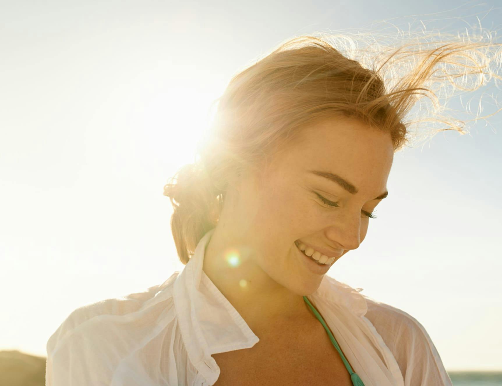 woman smiling with sun behind her