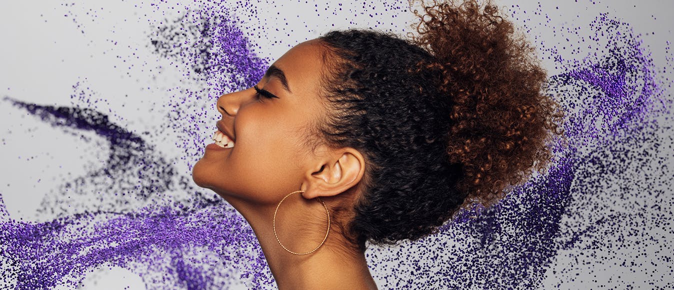 Side portrait of a cheerful woman against a purple particle background