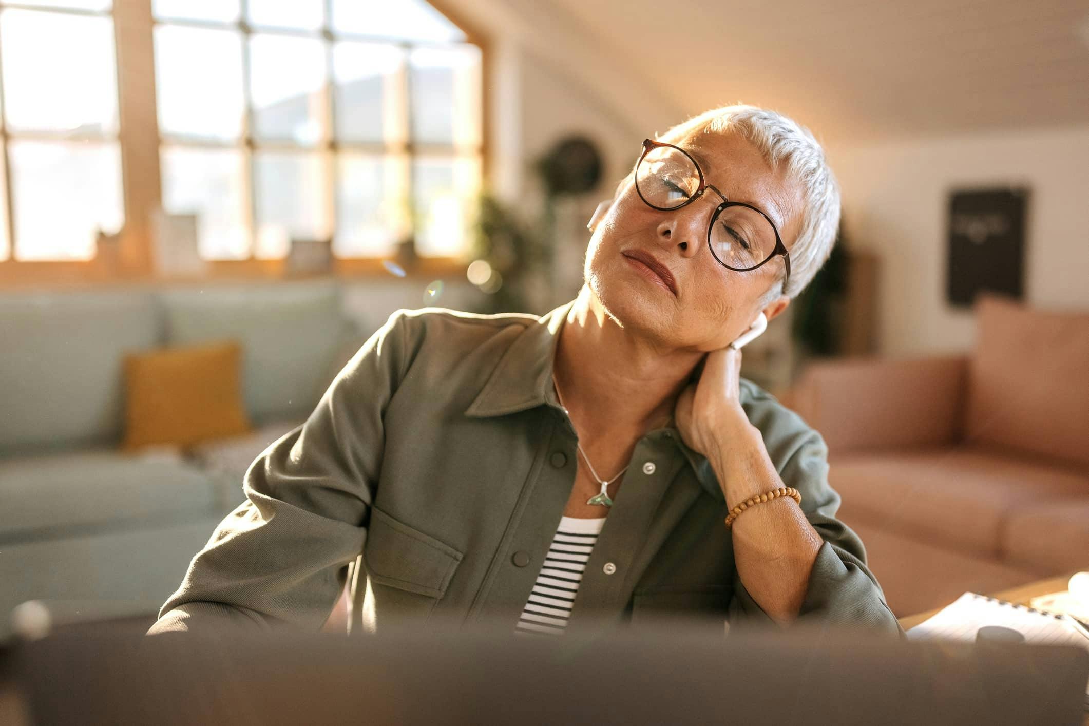 Woman experiencing neck pain while holding neck
