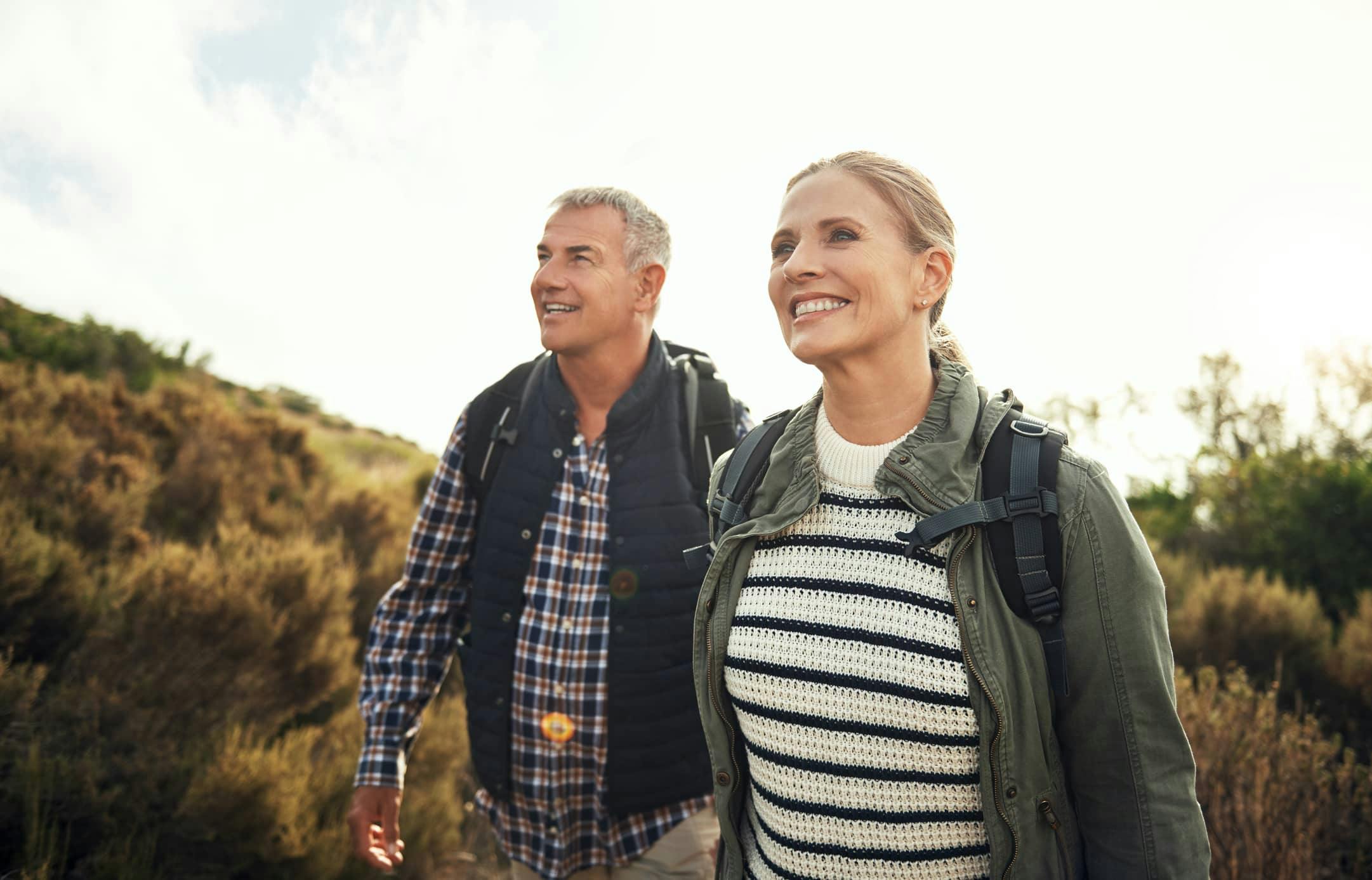 Older man and woman smiling and hiking together