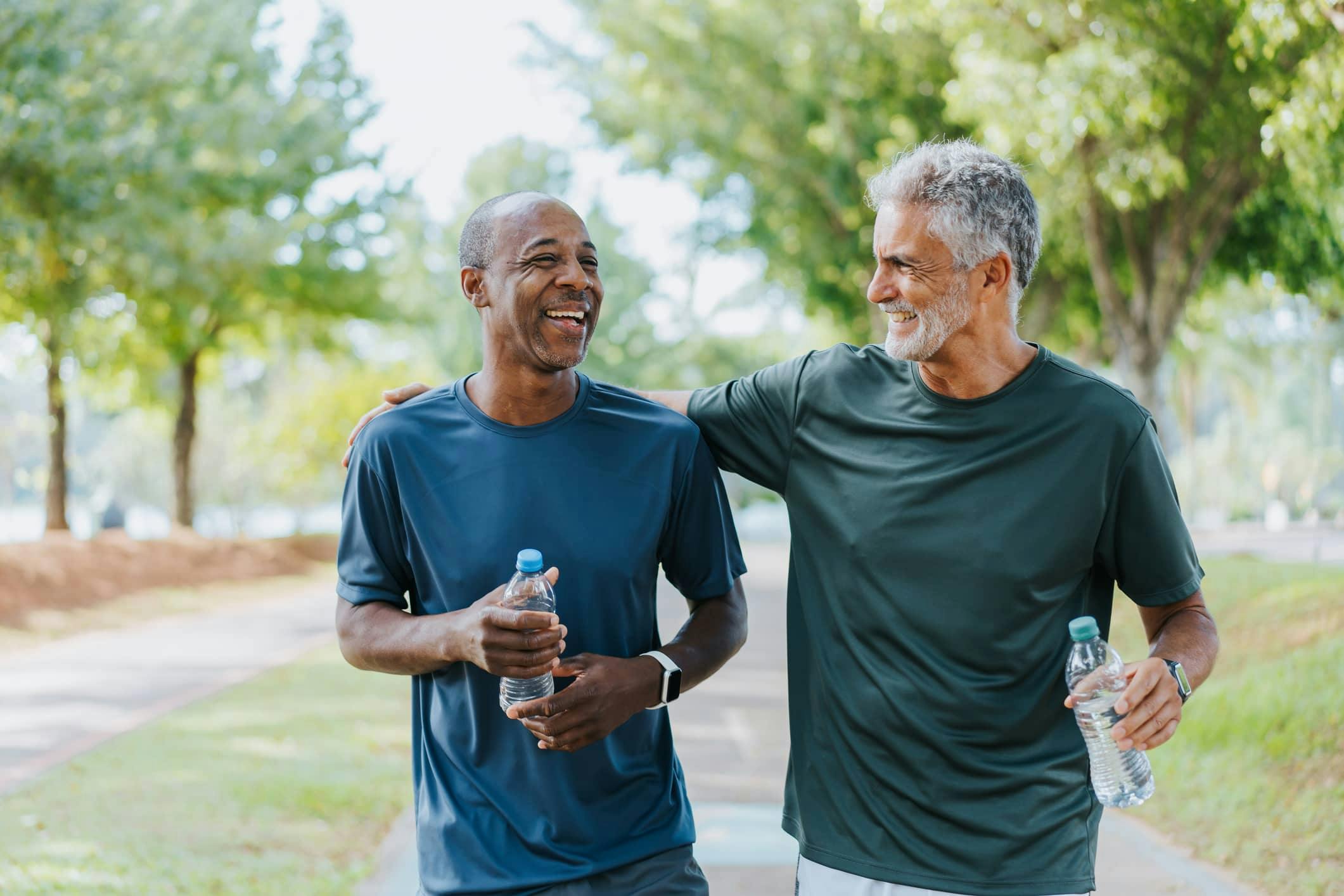 two older men smiling and jogging while holding water bottles
