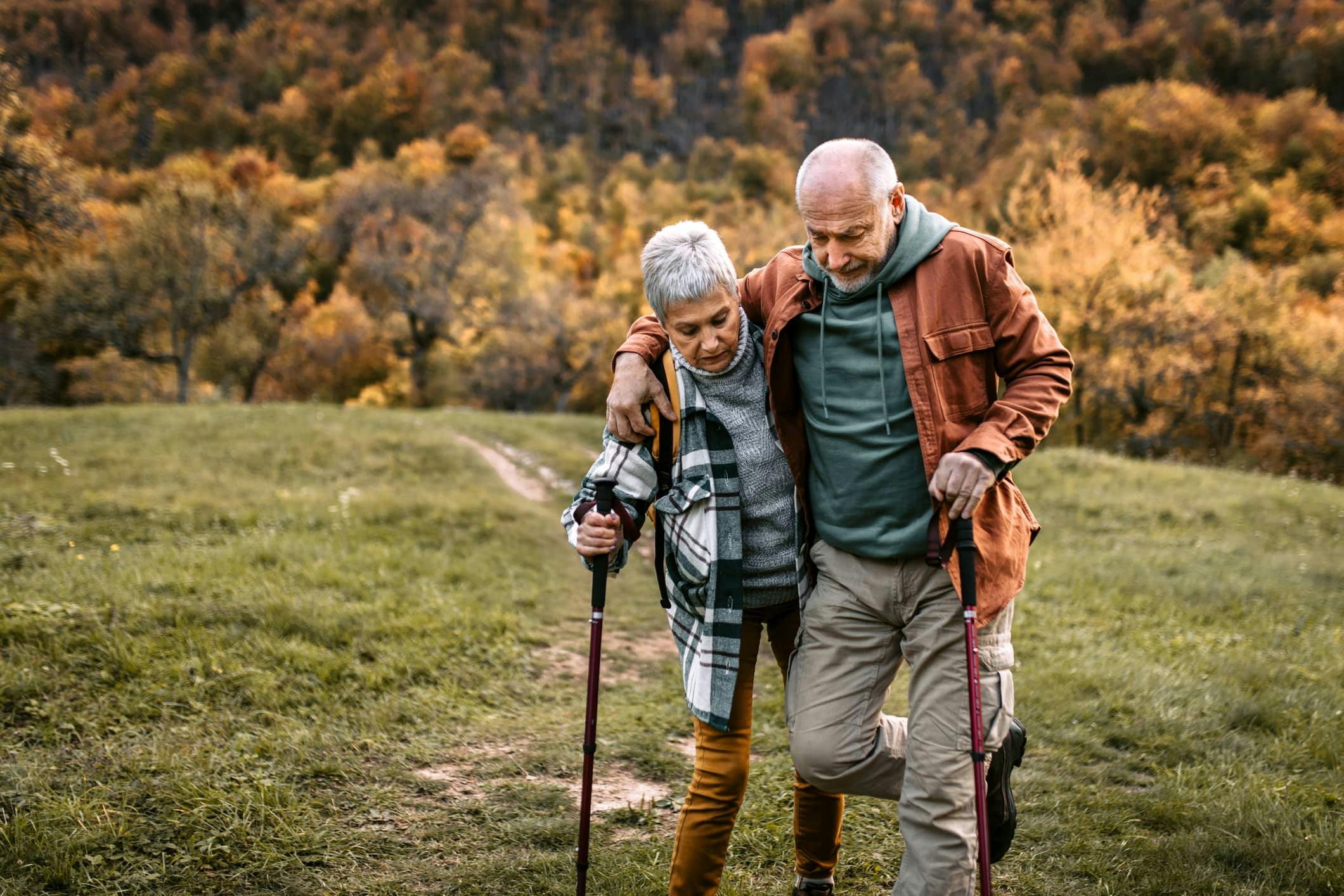 Older couple hiking and holding each other up