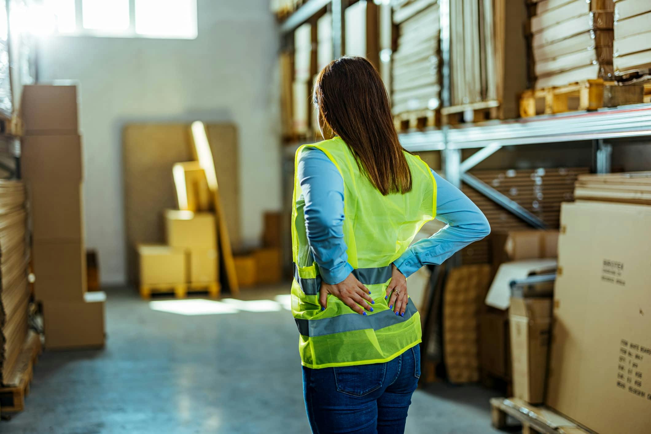woman holding lower back at warehouse