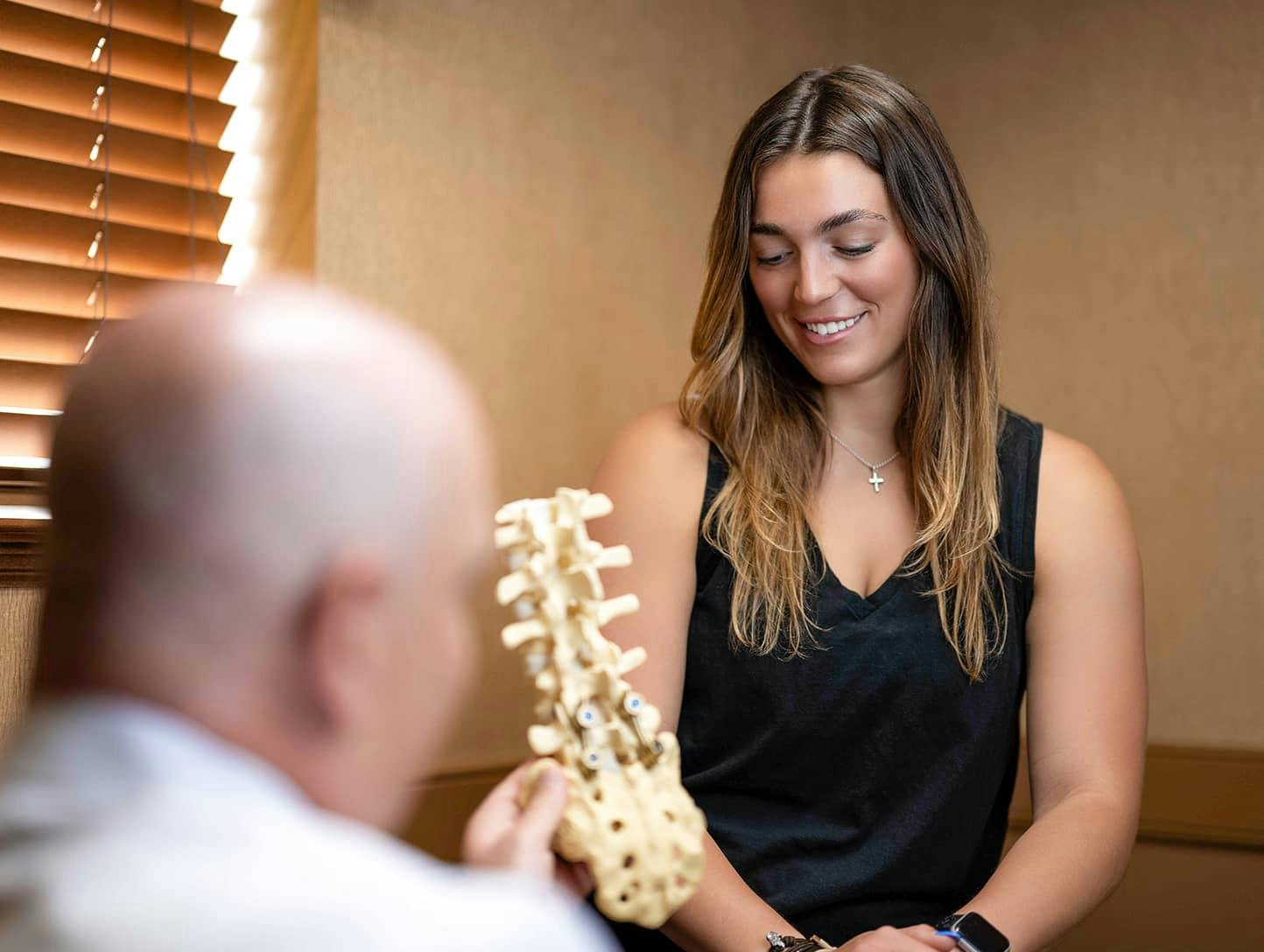 patient smiling while looking at Spine Anatomical Model
