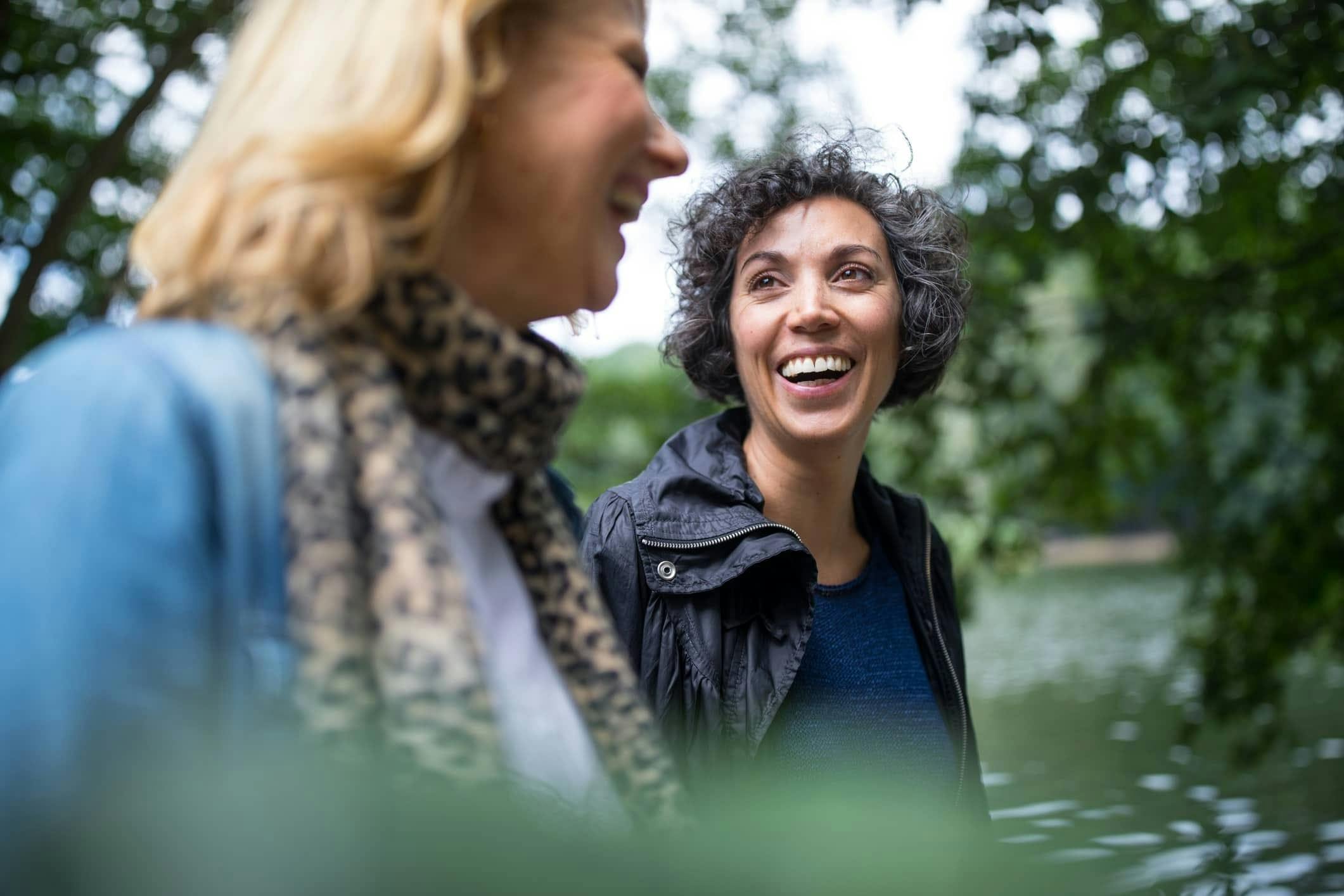 Two women smiling and walking through the park