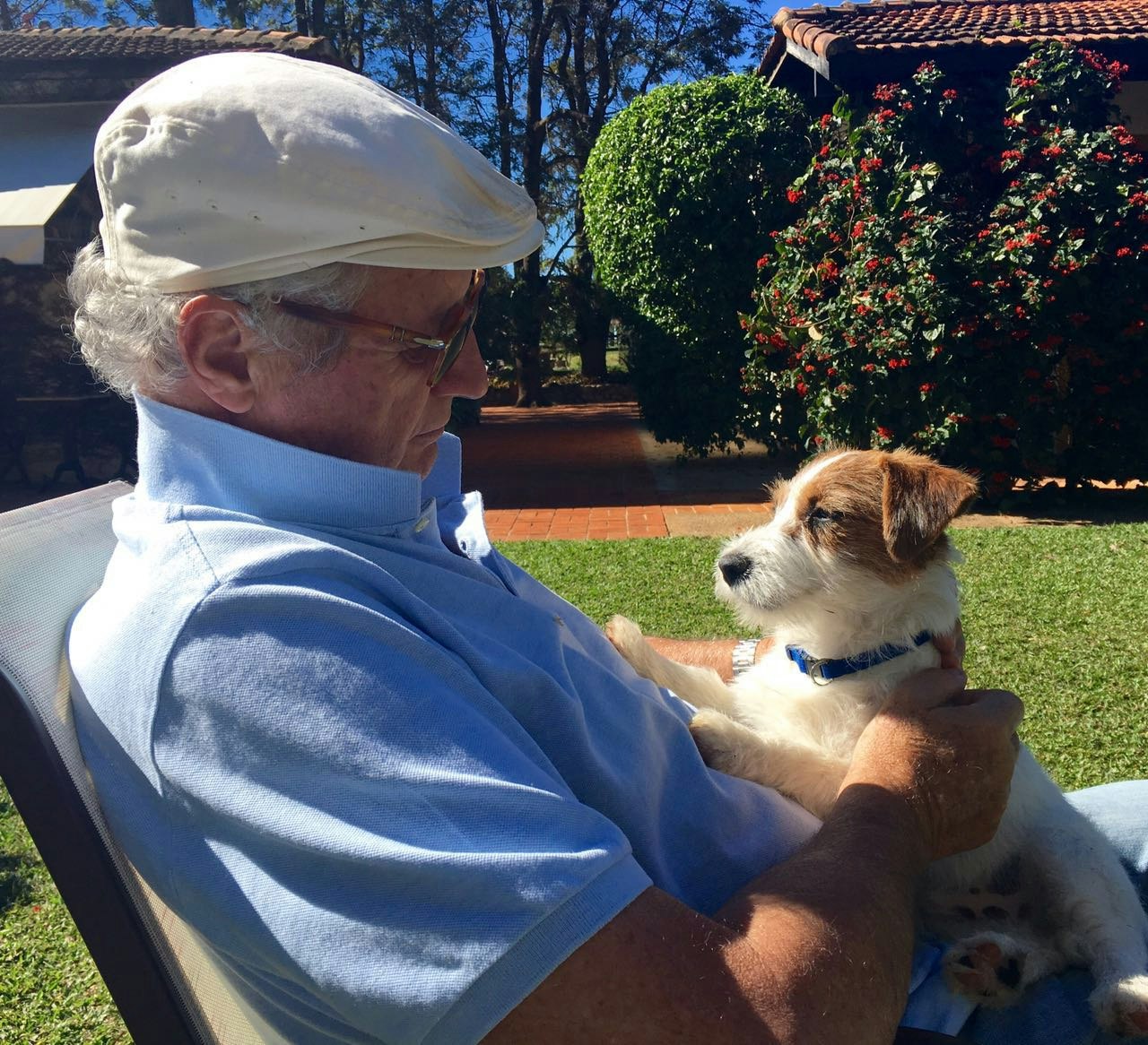 Um senhor sentado na companhia de seu cão jack russell