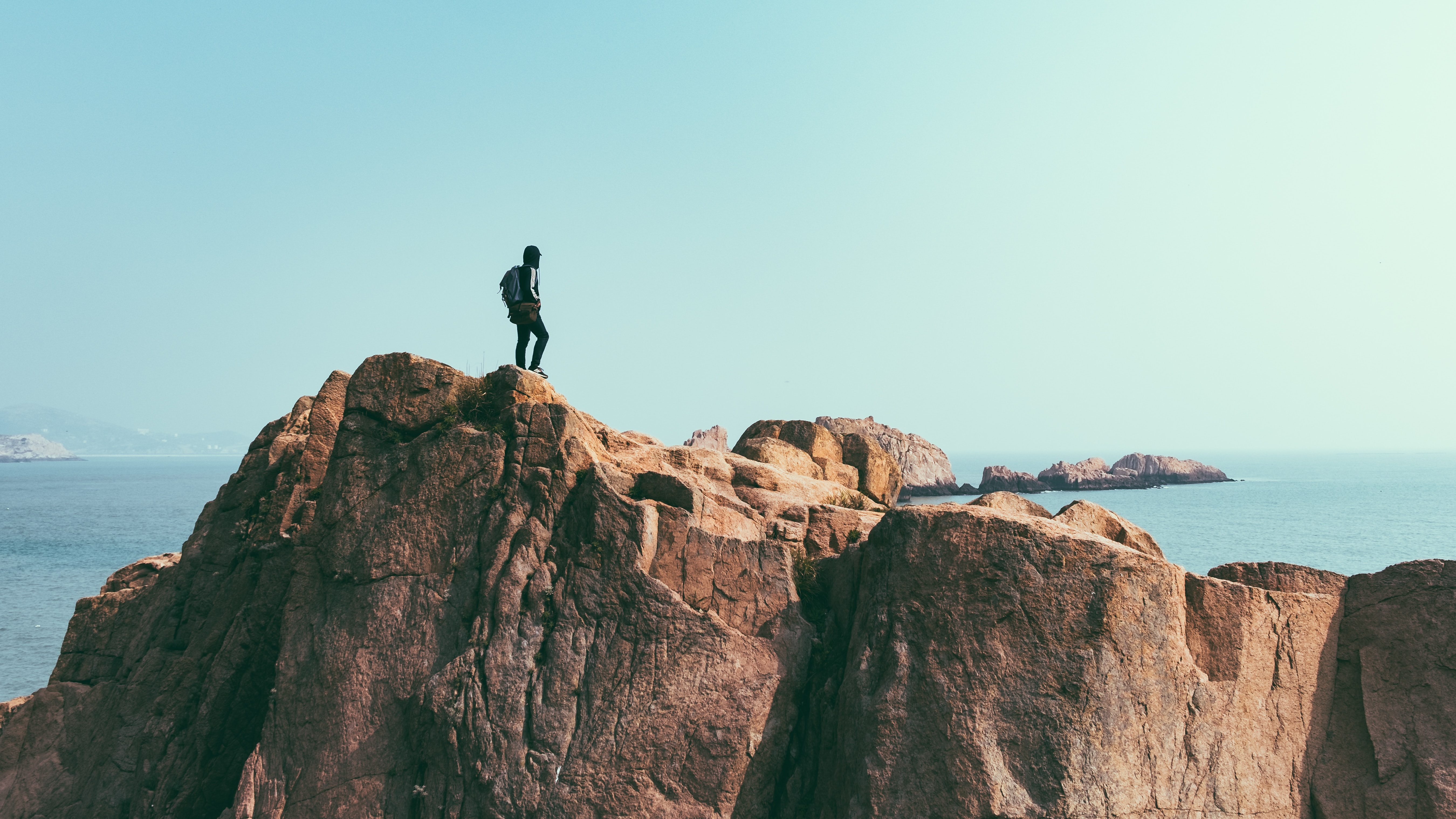 man on top of a cliff above the sea