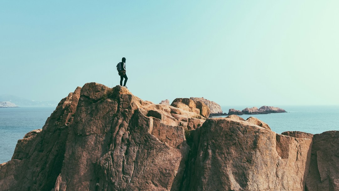 man on top of a cliff above the sea