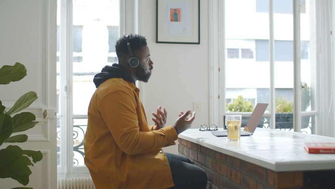Man wearing headphones and yellow shirt making a sales call