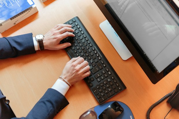 arms in a suit wearing a wrist watch hovering over a keyboard
