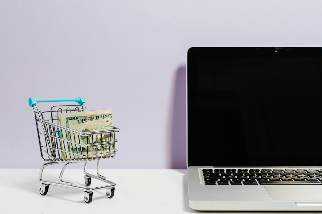 mini shopping cart holding money next to a laptop