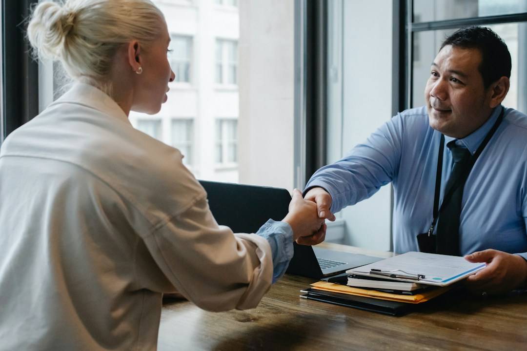 blonde business woman shaking hand of man in shirt and tie