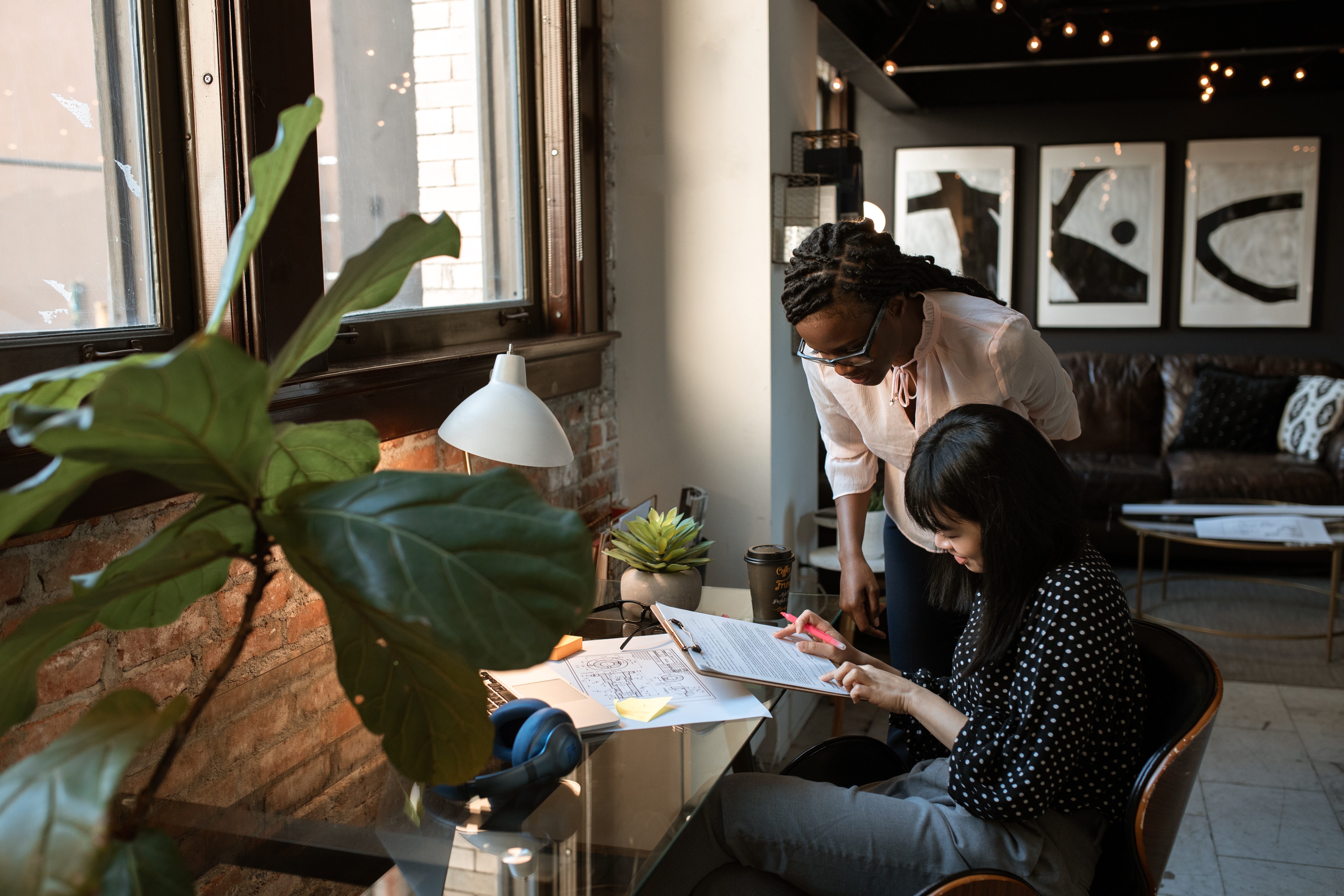 two woman looking at a paper together in a modern offic space