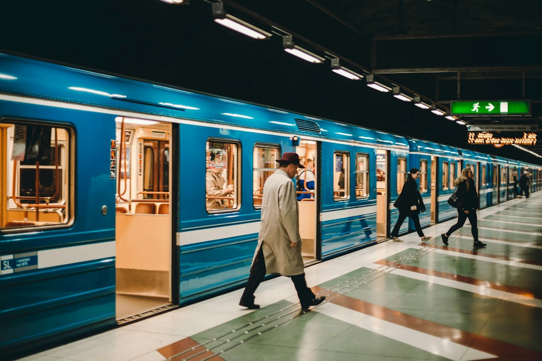 a blue train with the doors open as a man along the platform in a long jacket and at