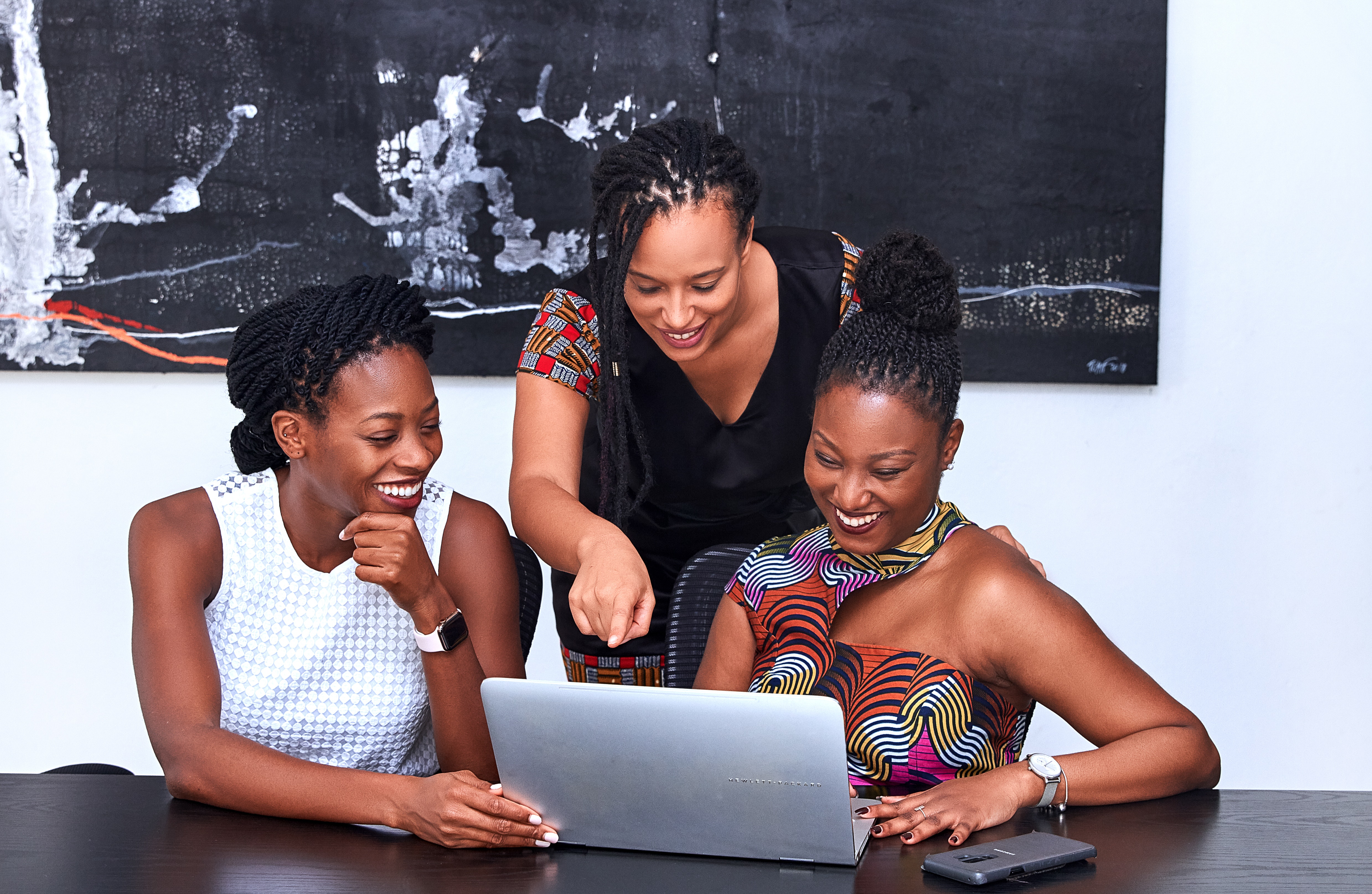 three women pointing at a computer smiling