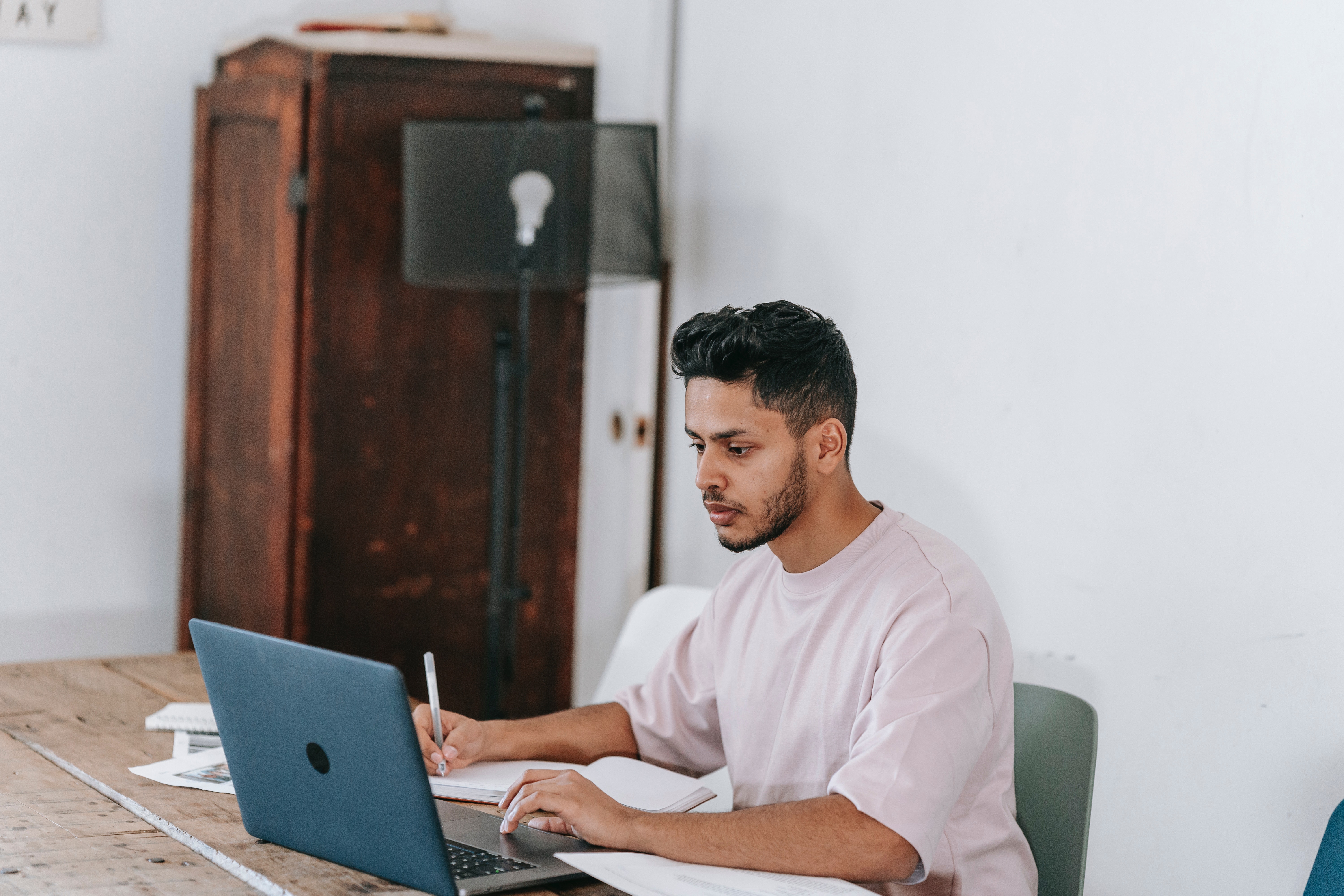 man looking at computer holding pen