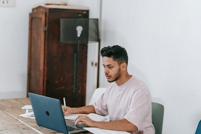 man looking at computer holding pen