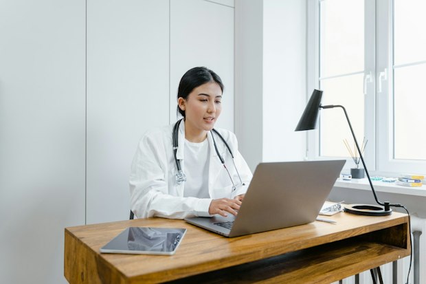 doctor sitting at a desk giving a video consultation
