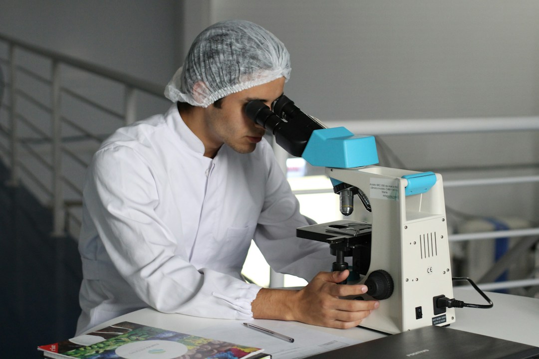 young man waering a hairnet looking at a telescope in a lab