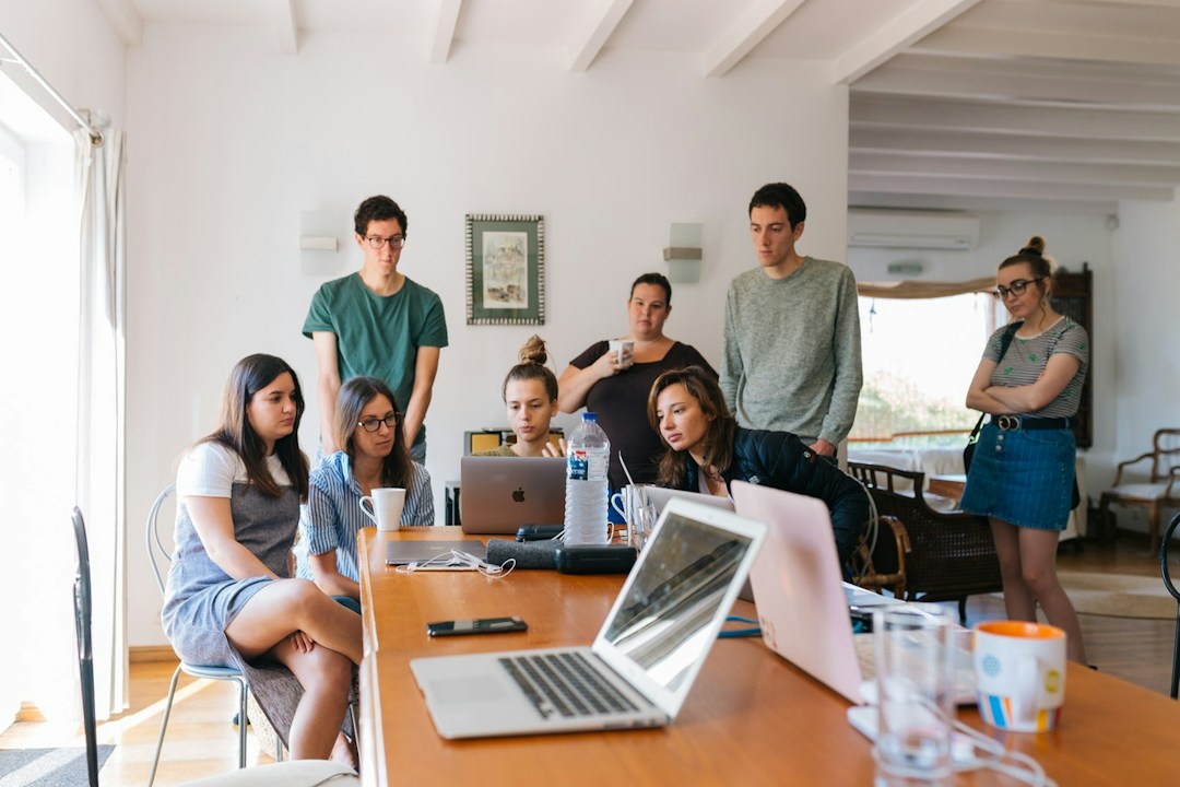 people gathered around a desk looking at computers