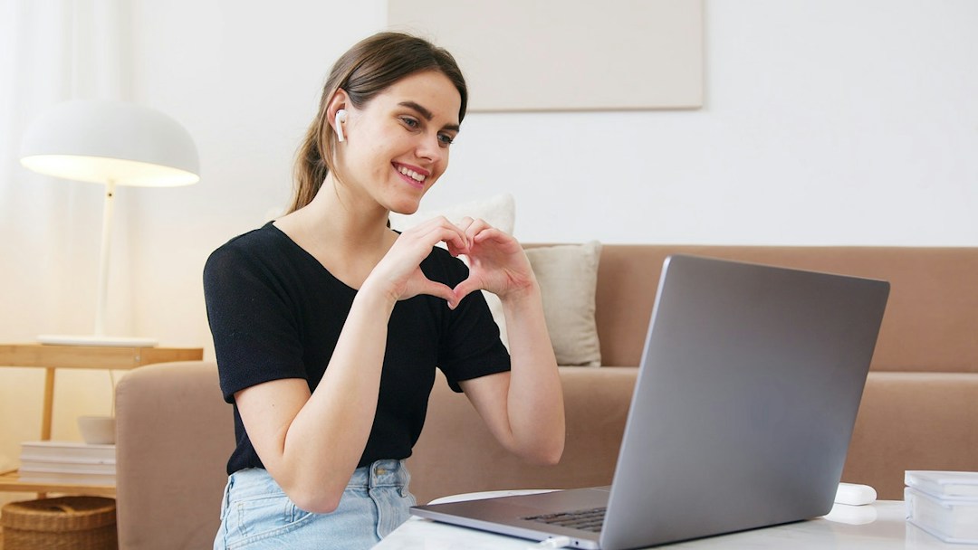 woman doing a heart symbol in a virtual meeting