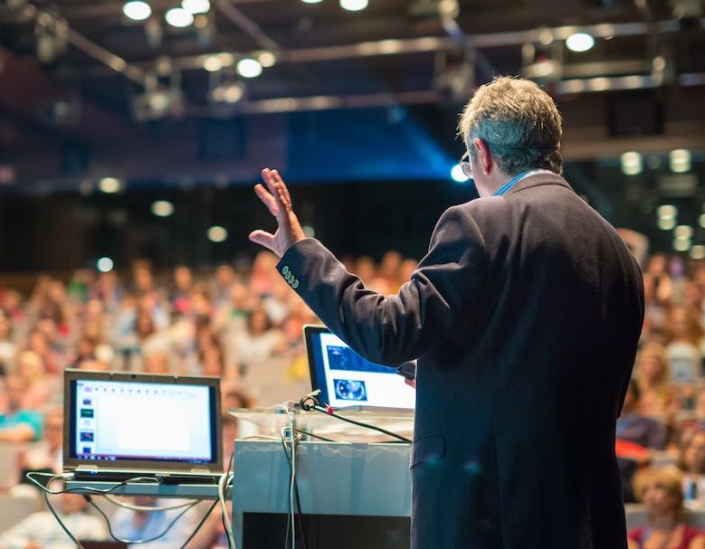 man hosting a hybrid virtual event in front of a crowd of people
