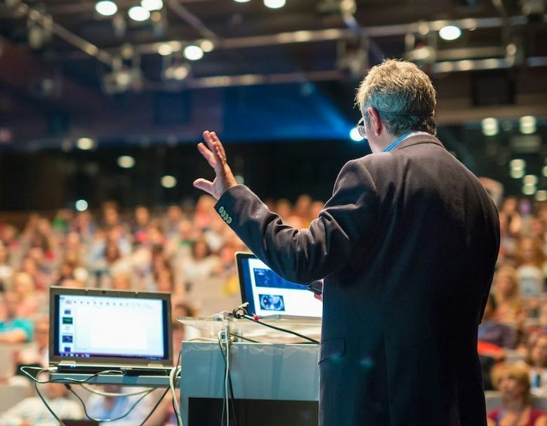 man hosting a hybrid virtual event in front of a crowd of people