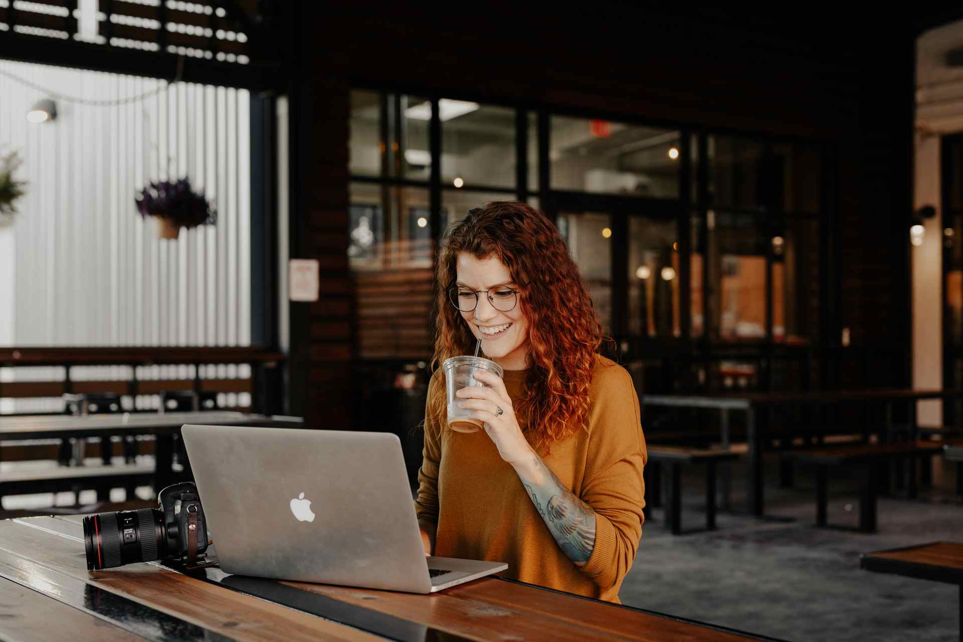 Mujer sonriente trabajando en laptop en cafetería moderna